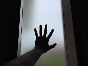 Close-up of hand touching glass window