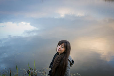 Portrait of young woman standing at lake