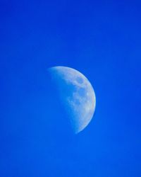 Low angle view of moon against clear blue sky