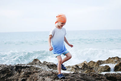 Full length of boy walking at rocks beach