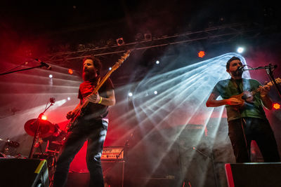 People standing on illuminated guitar at night