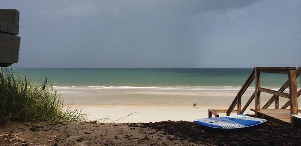 Deck chairs on beach against sky