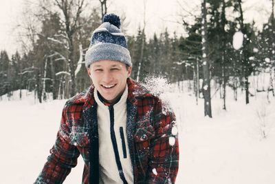 Portrait of smiling young woman standing in snow