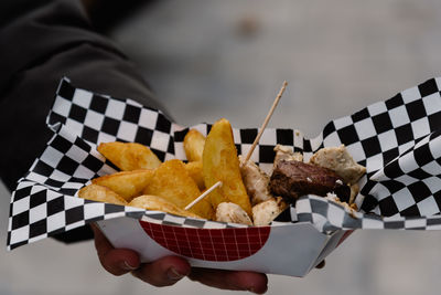 Cropped image of woman hand holding meat with french fries