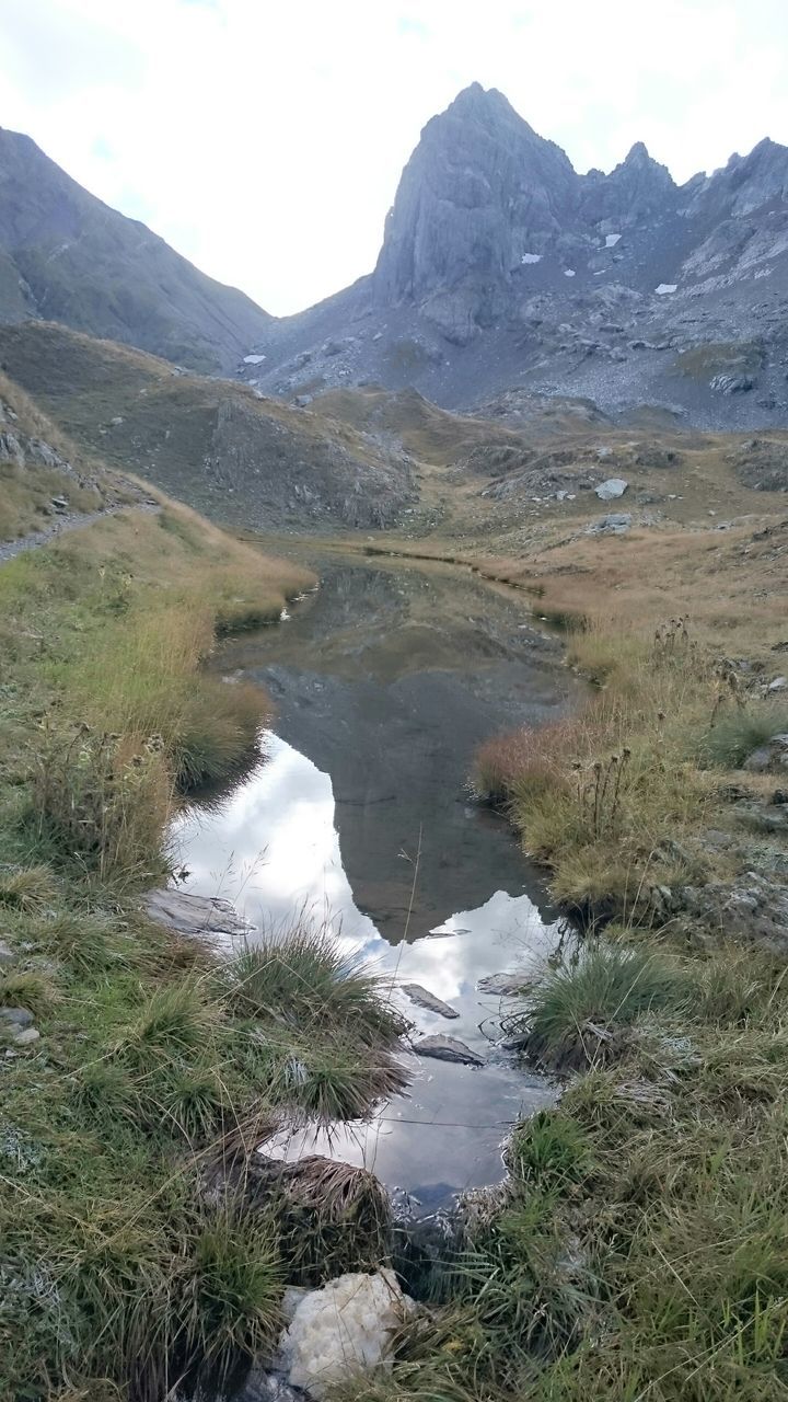 water, mountain, tranquility, tranquil scene, lake, scenics, reflection, beauty in nature, mountain range, nature, grass, landscape, sky, non-urban scene, stream, idyllic, river, day, countryside, outdoors