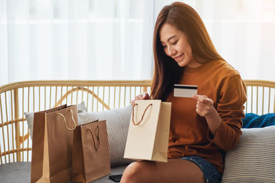 Young woman using digital tablet while sitting on sofa at home