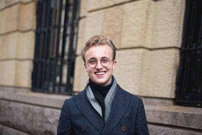 Portrait of young man standing against wall