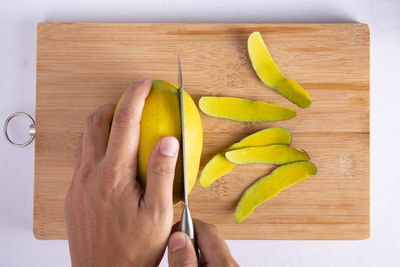 Close-up of hand holding fruits on cutting board