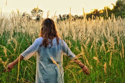 Rear view of woman standing on field against sky