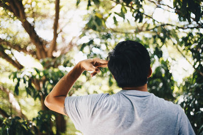 Rear view of man photographing against trees