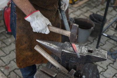 Midsection of blacksmith using hammer