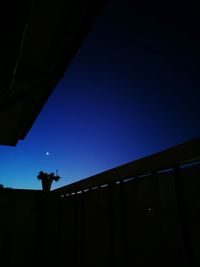 Low angle view of silhouette perching on building against clear sky