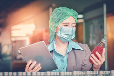 Woman using digital tablet while inspecting drinks in factory