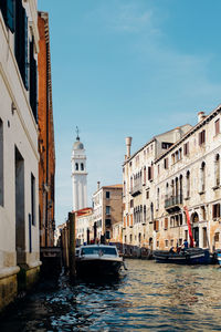 Boats moored in grand canal amidst old buildings against clear sky