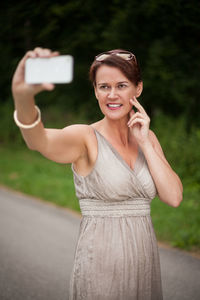 Smiling mature woman taking selfie with smart phone