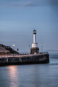 Lighthouse by sea against sky