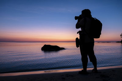 Silhouette woman photographing at beach