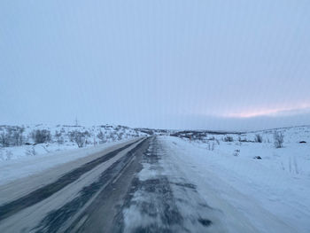 Road amidst snowcapped landscape against sky