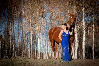 Woman standing by horse at forest