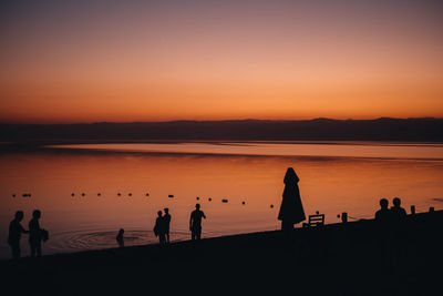 Silhouette people on beach against sky during sunset