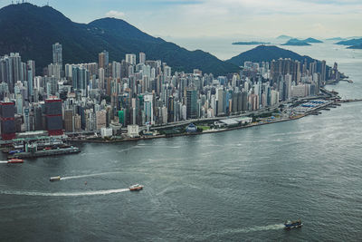 Boats in sea by buildings against sky in city