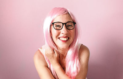 Woman with pink wig smiling happily on pink background