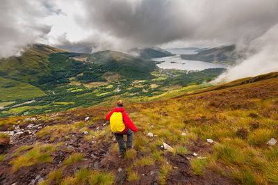 Rear view of man standing on mountain against sky