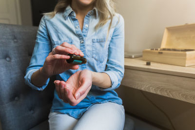 Midsection of woman holding mobile phone while sitting on sofa at home