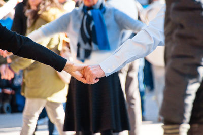 Low section of people holding hands while dancing 