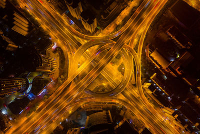 High angle view of illuminated street amidst buildings in city at night