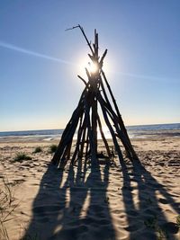 Traditional windmill on beach against sky during sunny day