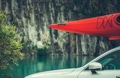 Close-up of red boat on car roof by lake