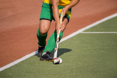Low section of man playing hockey on playing field