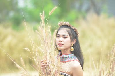 Portrait of young woman looking away on field