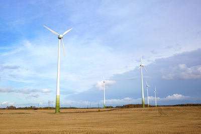 Low angle view of windmills on landscape against sky