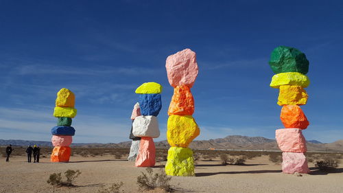 Tourists standing by colorful rock stacks against sky