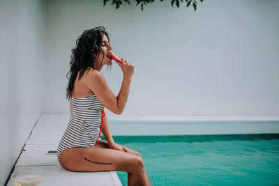 Woman sitting in swimming pool against sea