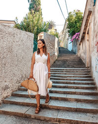 Young woman in white summer dress walking down the street of an old town.