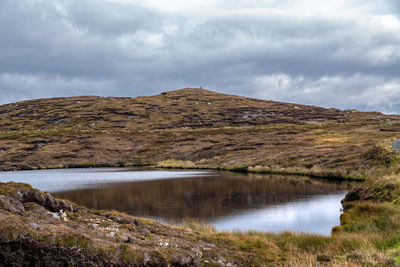 Scenic view of lake by mountain against sky