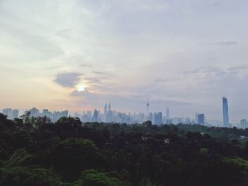 Trees and buildings against sky during sunset