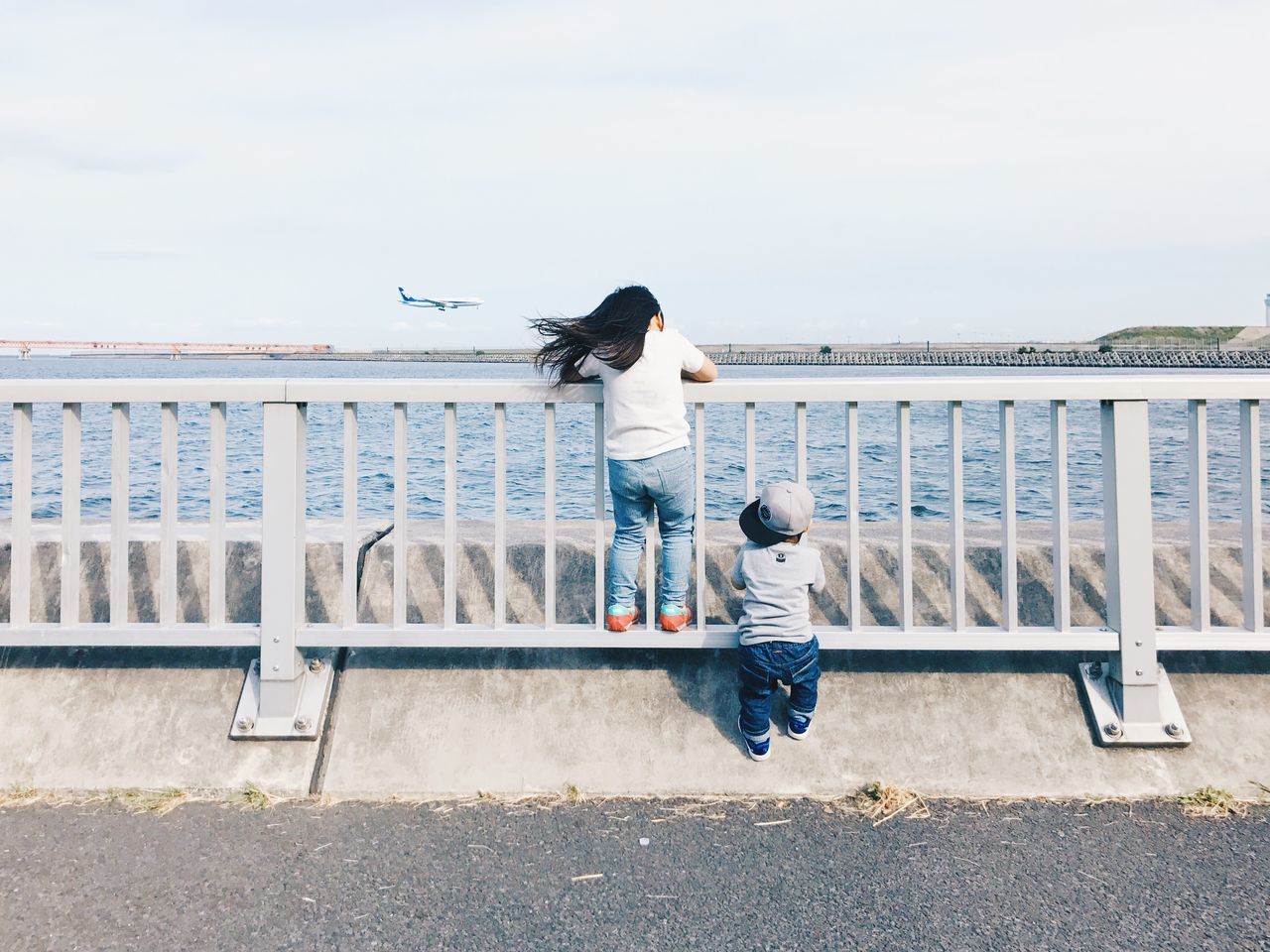 real people, railing, leisure activity, full length, water, outdoors, day, two people, casual clothing, togetherness, lifestyles, rear view, motion, standing, sea, women, men, sky, built structure, architecture, young women, horizon over water, nature, friendship, building exterior, city, young adult