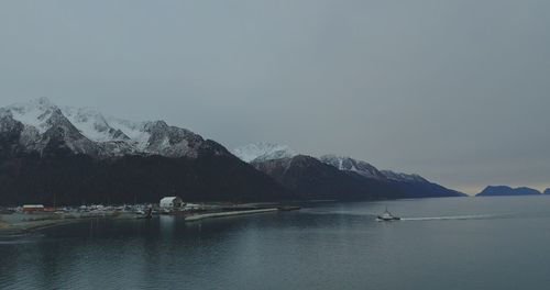 Scenic view of lake by snowcapped mountains against sky