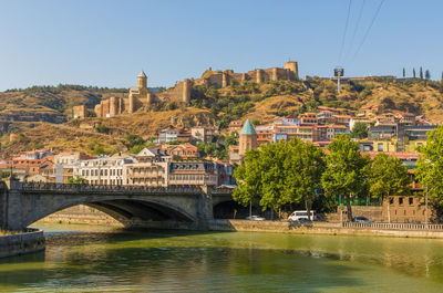 Arch bridge over river by buildings against clear sky
