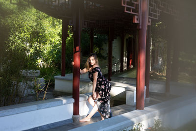 Woman standing by plants against trees