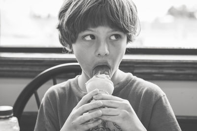 Boy looking away while eating ice cream at home