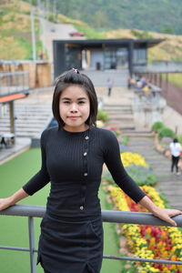 Portrait of smiling young woman standing by railing on observation point