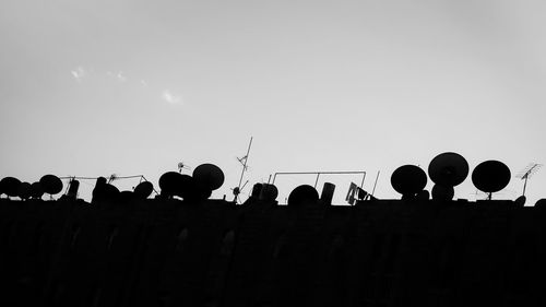 Low angle view of silhouette birds perching against sky