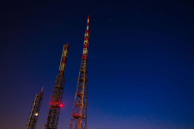 Low angle view of communications tower against sky at night