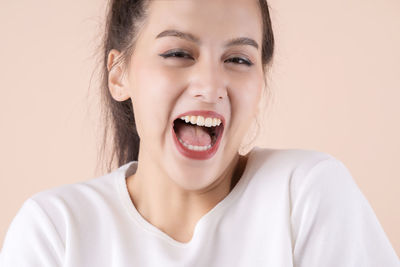 Close-up portrait of young woman against gray background