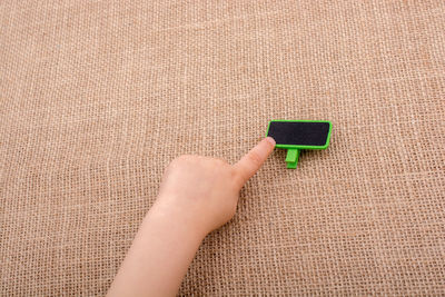 Cropped hand of child pointing at small tag on jute